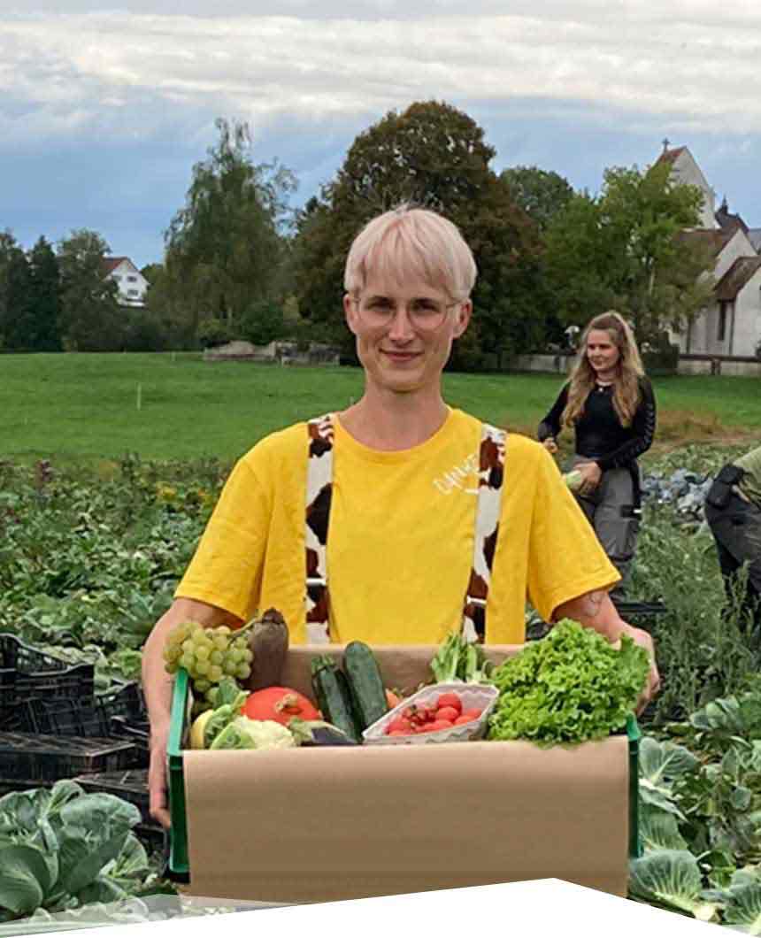 Fahrerin vom Hof Dinkelberg mit einer gepackten Biokiste auf einem Feld